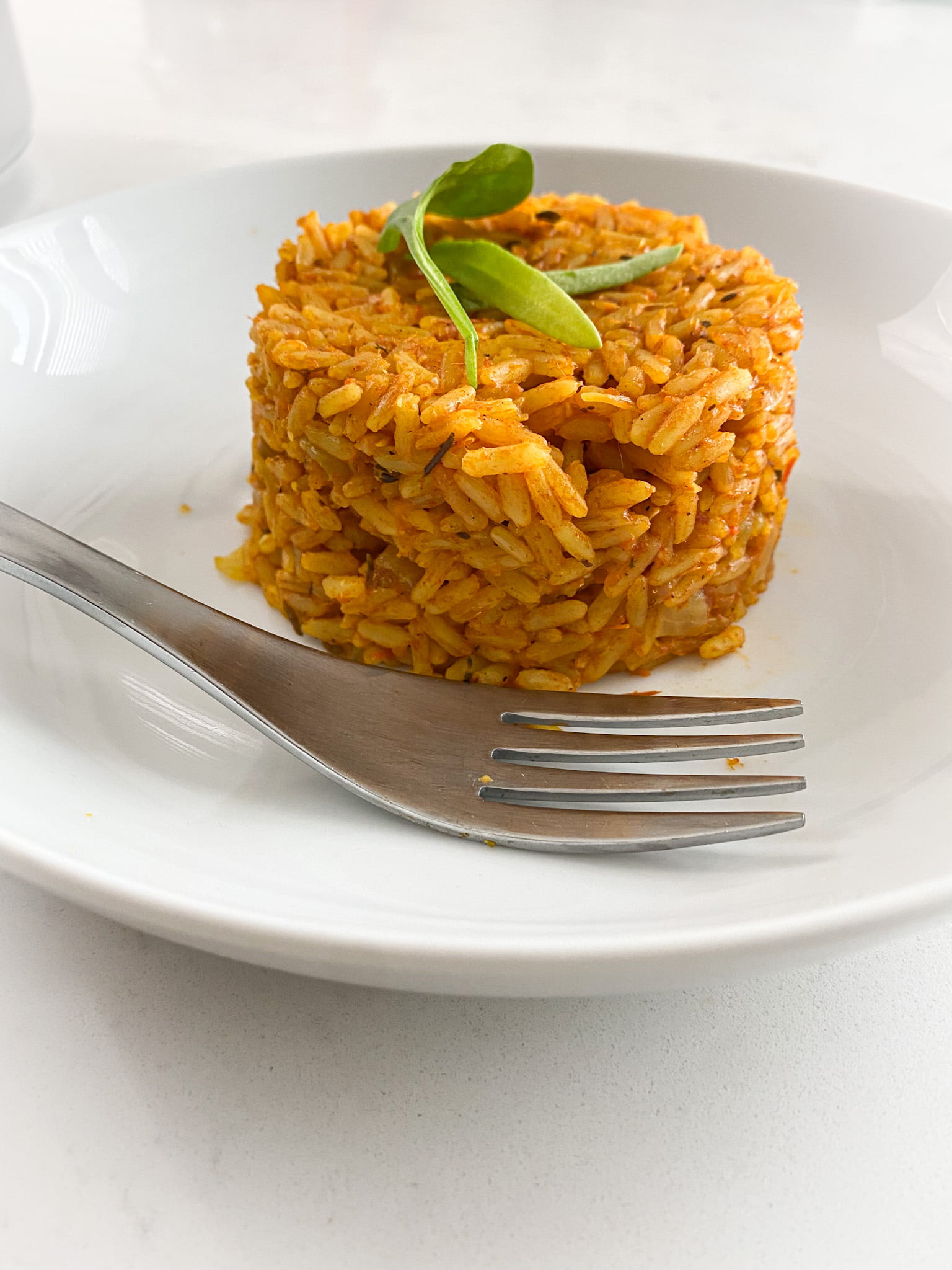 portioned out plate of jollof rice with a silver fork