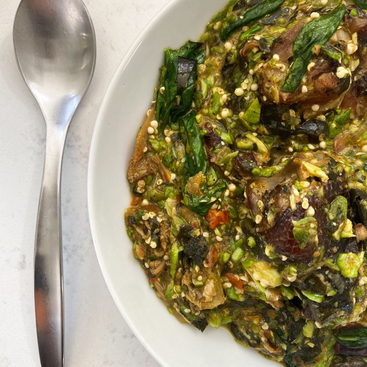 plated okra soup with a silver spoon to the left