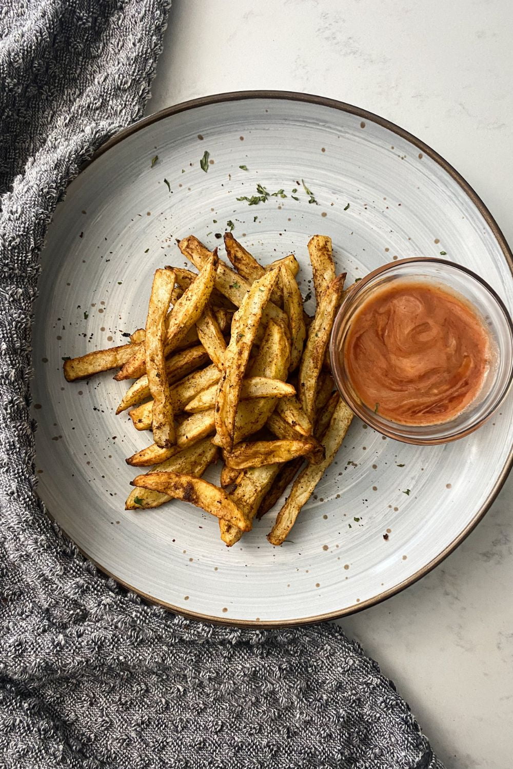 plated jerk french fries on a gray plate with dipping sauce