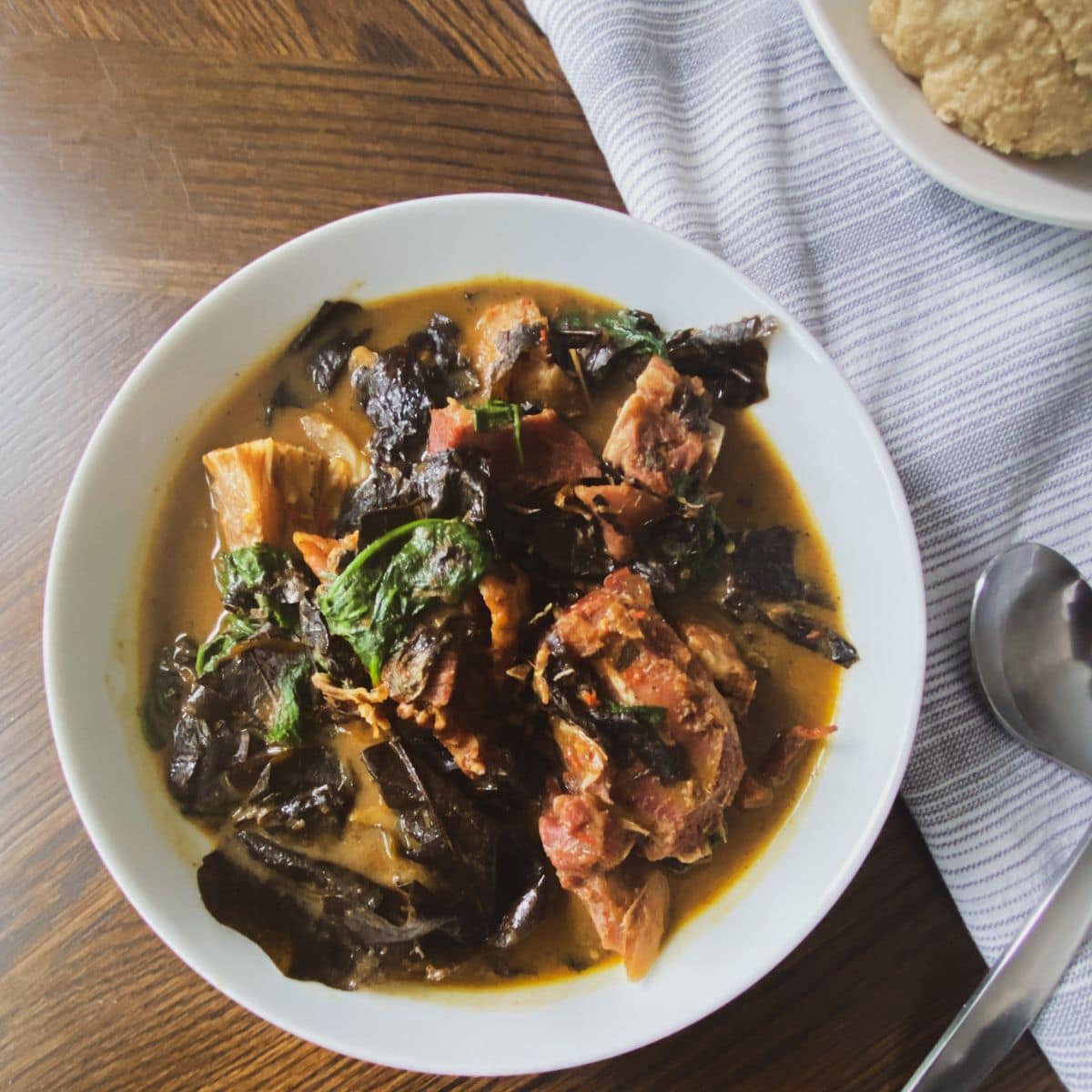 prepared Oha soup in a white bowl with utensils and gray towel to the right side